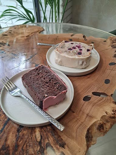 Chocolate cake with pink frosting and berry cake with white icing on a wooden table.